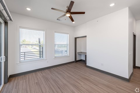 A room with a ceiling fan and wooden flooring.